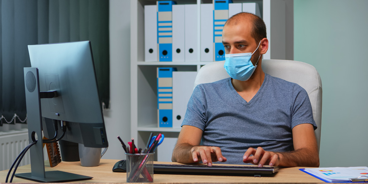 Man wearing mask working at computer